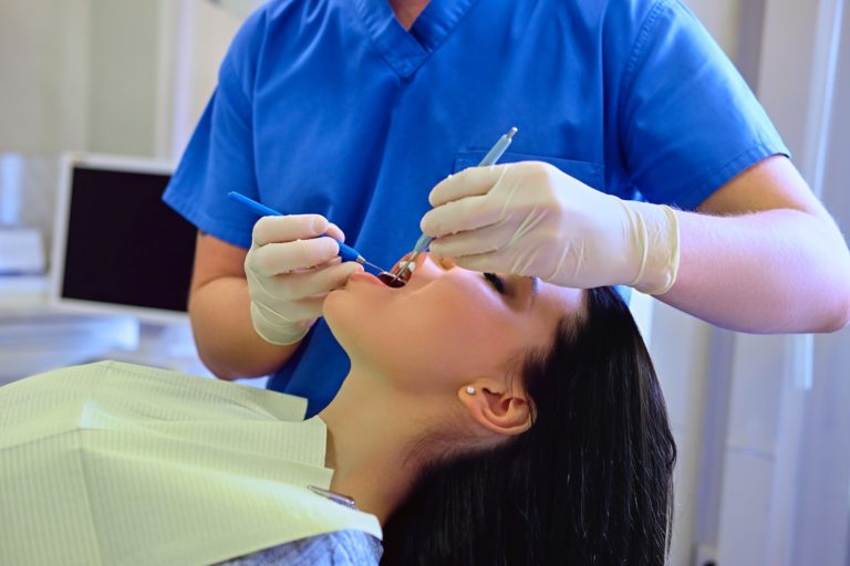 Dentist examining female's teeth in dentistry.