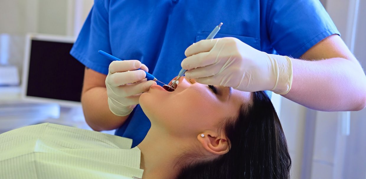 Dentist examining female's teeth in dentistry.